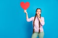 Portrait of thoughtful interested youth girl with long pigtails hold red paper card heart gift for valentine day think