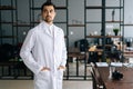 Portrait of thoughtful male doctor wearing white medical uniform standing in hospital office, looking away. Royalty Free Stock Photo