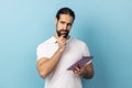 Man holding paper notebook, having thoughtful facial expression, planning. Royalty Free Stock Photo