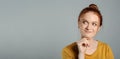 Portrait of thoughtful red haired woman with charming smile on grey background Royalty Free Stock Photo