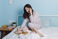 Portrait of thoughtful serious confident brunette friendly smart girl sitting on bed talking on phone, drinking coffe Royalty Free Stock Photo