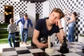 Teenager solving conundrum in quest room stylized under chessboard