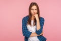 Portrait of thoughtful upset girl in checkered shirt pondering serious issues, looking with uncertain hesitant expression