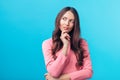 Portrait of thoughtful wondering woman looking sideways isolated over blue background