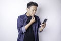 Portrait Of A Thoughtful Young Asian Man Wearing Navy Blue Shirt Looking Aside While Holding Smartphone