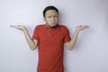 Portrait of a thoughtful young casual man wearing a red shirt pointing aside isolated over white background Royalty Free Stock Photo