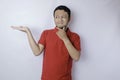 Portrait of a thoughtful young casual man wearing a red shirt pointing aside isolated over white background Royalty Free Stock Photo