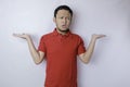 Portrait of a thoughtful young casual man wearing a red shirt pointing aside isolated over white background Royalty Free Stock Photo