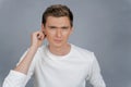 Portrait of a thoughtful young man in a white t-shirt over isolated gray background. Royalty Free Stock Photo