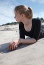 Portrait of young girl in black dress with long blonde hair lying on beach Royalty Free Stock Photo