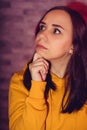 Portrait of thoughtful young woman on backlit background. Close up of cute brunette propping up her chin in reflections.