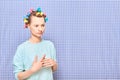 Portrait of thoughtful young woman with colorful hair curlers on head Royalty Free Stock Photo