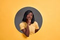 Portrait of a thoughtful young  woman looking up in a round hole circle in orange background. Copy space Royalty Free Stock Photo