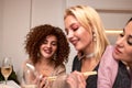 Portrait of three beautiful young women eating japanese food and drinking wine at home. Royalty Free Stock Photo