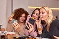 Portrait of three beautiful young women eating japanese food and drinking wine at home. Royalty Free Stock Photo