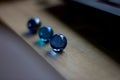 A portrait of three blue marbles, each having another shade of blue, on a wooden surface. Shining a bit of blue light onto the Royalty Free Stock Photo