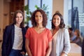 Portrait Of Three Businesswomen Standing In Modern Open Plan Office Together