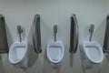 Three ceramic urinals inside the men`s public toilet