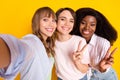 Portrait of three charming cheerful ladies make selfie fingers show v-sign isolated on yellow color background Royalty Free Stock Photo