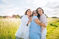 Portrait of three cheerful smiling women embracing during outdoor walking. They looking at the camera. Woman friendship, relations