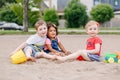 Three cute Caucasian and hispanic latin toddlers babies children sitting in sandbox playing with plastic colorful toys Royalty Free Stock Photo