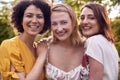 Portrait Of Three Female Friends Sitting Outdoors Together And Catching Up In Summer Garden At Home 