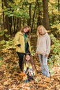 Portrait of three generations of happy beautiful woman and dog looking at camera, hugging and smiling in autumn nature. Royalty Free Stock Photo