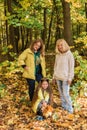 Portrait of three generations of happy beautiful women and dog looking at camera, hugging and smiling in autumn nature. Royalty Free Stock Photo