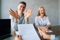 Portrait of three happy smiling colleagues conducting business presentation while sitting at table with laptop and paper Royalty Free Stock Photo