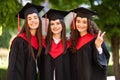 Portrait of three happy students in graduation gowns on university campus Royalty Free Stock Photo