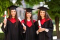 Portrait of three happy students in graduation gowns on university campus Royalty Free Stock Photo