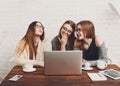 Portrait of three laughing girlfriends with laptop.