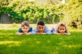 Portrait of three little children lying on a green grass