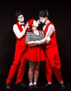 Portrait of three mime artists, isolated on black background. A man joins the heads of a man and a woman in a kiss Royalty Free Stock Photo