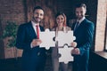 Portrait of three nice chic classy elegant stylish cheerful executive managers holding in hands fitting big large puzzle Royalty Free Stock Photo