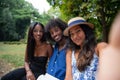 Portrait of three smiling friends sitting on a bench taking a selfie in a public park Royalty Free Stock Photo