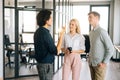 Portrait of three successful young colleagues standing in modern loft office talking and discussing business issues Royalty Free Stock Photo