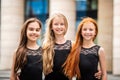 Portrait of three teenage girls with loose hair, blonde, redhead and brunette Summer on street. Vloses develop in wind