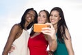 Portrait of three women taking selfies with a smartphone.