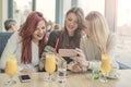 Portrait of three young beautiful women using mobile phone at co Royalty Free Stock Photo