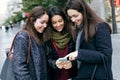 Portrait of three young beautiful women using mobile phone. Royalty Free Stock Photo