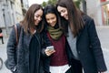 Portrait of three young beautiful women using mobile phone. Royalty Free Stock Photo