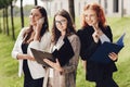 Portrait of three young successful businesswomen standing outdoors near office building on a sunny day. Royalty Free Stock Photo