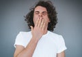 Portrait of tired or bored Caucasian young male model with curly hair covering mouth while yawning, feeling exhausted after