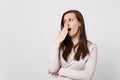 Portrait of tired boring young woman in light clothes looking aside, yawning covering mouth with hand on white