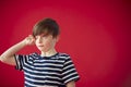 Portrait Of Tired Boy Rubbing Eyes Against Red Studio Background