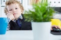 Portrait of tired business child wearing formal shirt and tie. Cute little boy covering his mouth with hands, imitating