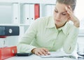 Portrait of a tired businesswoman looking at a stack of folders on the desk. Royalty Free Stock Photo