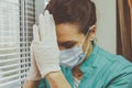 Portrait of Tired Doctor woman in medical mask, gloves and doctor`s suit closed her eyes Royalty Free Stock Photo