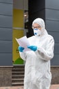 Portrait of tired exhausted female doctor, scientist or nurse wearing face mask and biological hazmat ppe suit reading Royalty Free Stock Photo